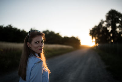 Portrait of young woman standing against sky during sunset