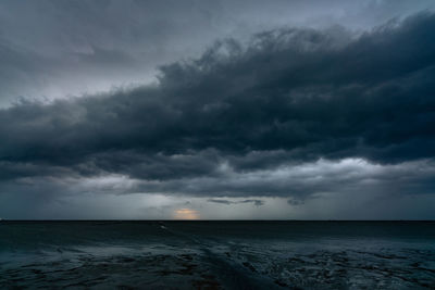 Landscape view of sea at tide and silhouette dark dramatic sunset sky and clouds in the evening. 