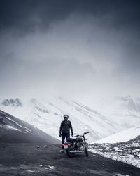 Man riding motorcycle on snowcapped mountain against sky