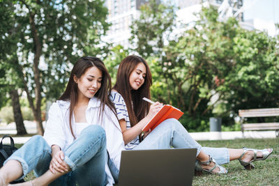 Friends using laptop while sitting at park