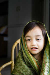 Portrait of cute asian toddler, kid, girl wearing traditional songket shawl.