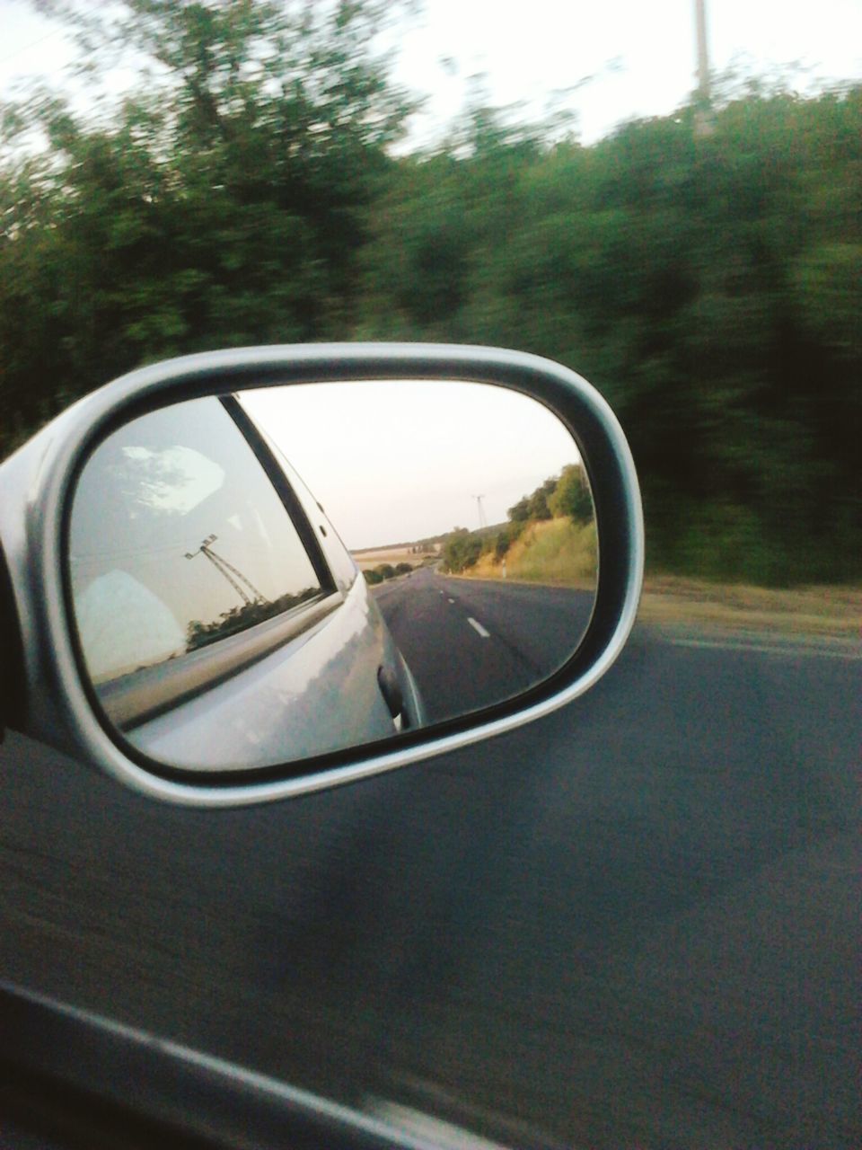 REFLECTION OF CAR ON SIDE-VIEW MIRROR AGAINST ROAD