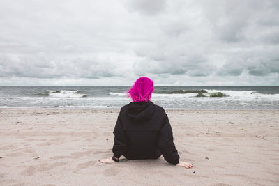 Rear view of woman on beach against sky