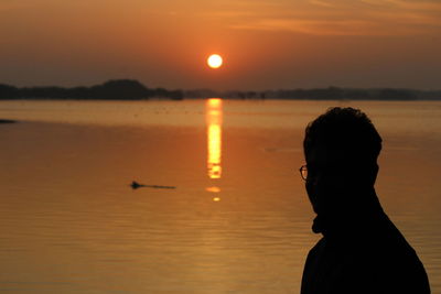 Silhouette man standing at beach during sunset