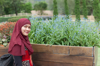 Smiling woman wearing hijab while standing by plants