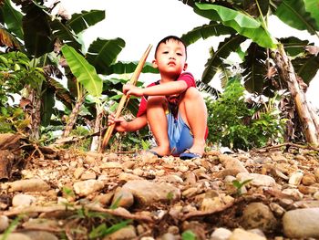 Portrait of boy crouching on footpath