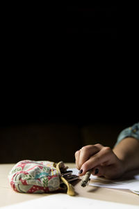 Cropped image of woman holding pen on table