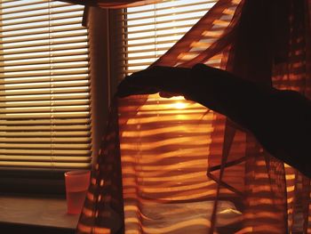 Midsection of person standing by window at home