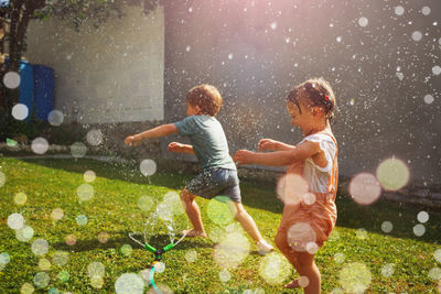 Rear view of boy playing with flowers