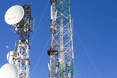 Low angle view of communications tower against blue sky