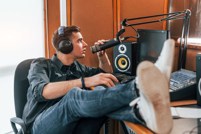 Talks and uses mic. young man is indoors in the radio studio is busy by broadcast.