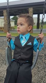 Cute boy sitting on swing at playground