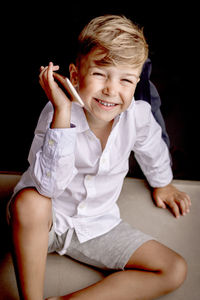 High angle view of happy kid talking on mobile phone while sitting on the floor.