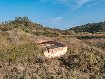 Abandoned boat on field against sky