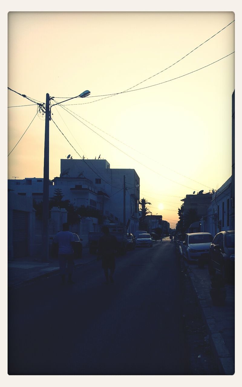 building exterior, transportation, architecture, built structure, car, street, transfer print, land vehicle, mode of transport, road, power line, sky, electricity pylon, street light, city, auto post production filter, sunset, city street, the way forward, clear sky