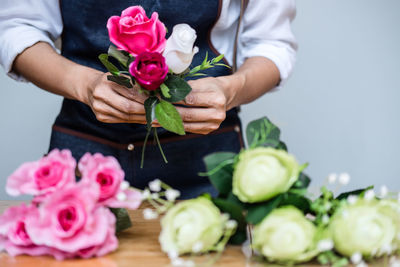 Midsection of man holding flowers at table