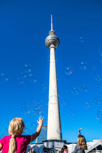 Low angle view of girls playing with bubbles against fernsehturm