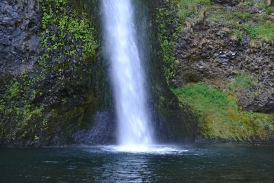 Scenic view of waterfall in forest against sky