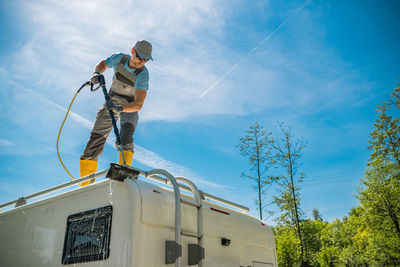 Low angle view of man skateboarding on roof against sky