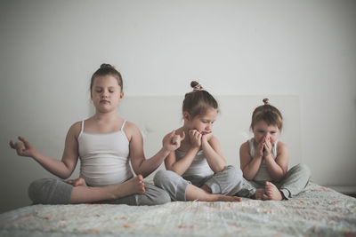 Three girls sisters are engaged in fun yoga, the concept of children, a healthy lifestyle