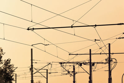 Low angle view of silhouette electricity pylon against sky during sunset