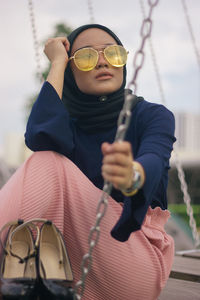 Portrait of man wearing sunglasses sitting on swing