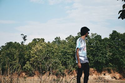 Full length of man standing on mobile phone against sky