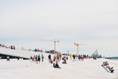 People at oslo opera house against clear sky