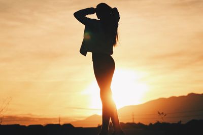 Silhouette woman standing against sky during sunset