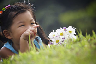 Girl with bunch of flowers lying on grassy field at park