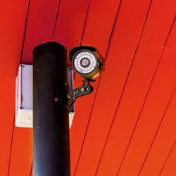 Low angle view of security camera against red ceiling