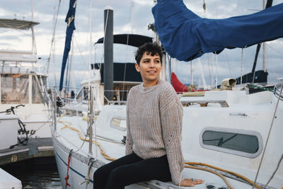 Thoughtful woman looking away while sitting on boat against cloudy sky during sunset