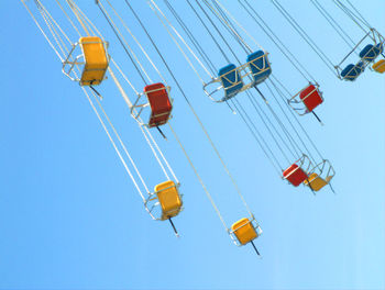 Low angle view of chain swing ride against clear blue sky