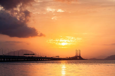 Silhouette of bridge over sea during sunset