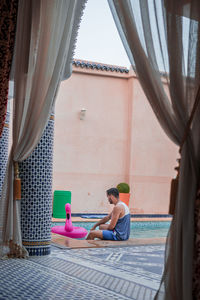 Rear view of woman sitting by swimming pool