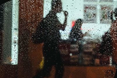 Silhouette woman seen through wet window in rainy season