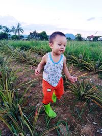 Cute boy on field against sky