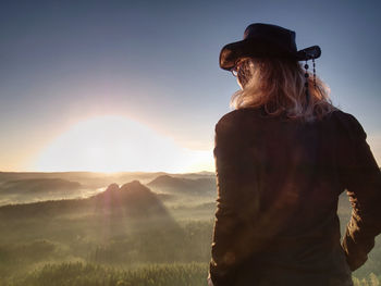 Fit body blond hair woman on top of high rocky mountain in evening. beautiful sunset autumn forest