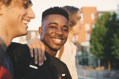 Portrait of smiling young man with friends standing in city