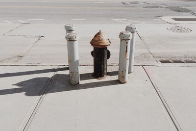 High angle view of fire hydrant amidst rusty metallic bollards on sidewalk