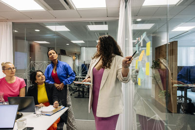 Female entrepreneur explaining colleagues while doing brainstorming session at office