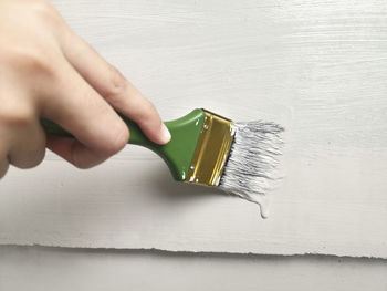 Cropped hand of woman holding paintbrush on table
