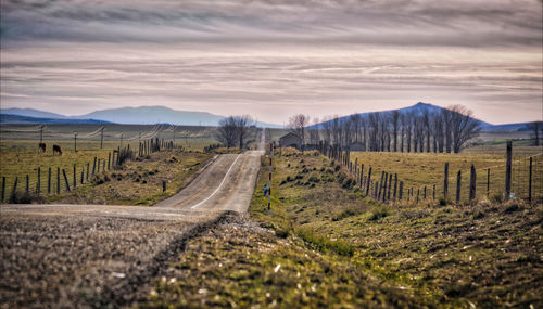 Road amidst field against sky