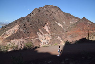 High angle view of woman standing on mountain road against sky