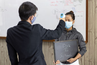 Young man examining girl with thermometer