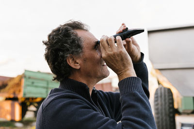 Man looking through refractometer at winery