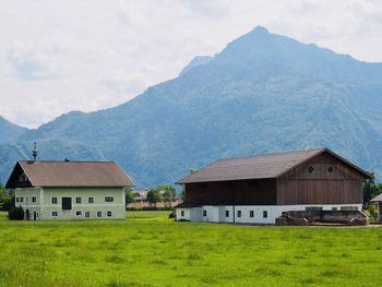 Houses on field by mountains against sky