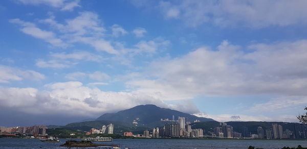 City at waterfront against cloudy sky