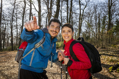Young smiling couple is hiking in the woods. the man points the right way to his girlfriend.