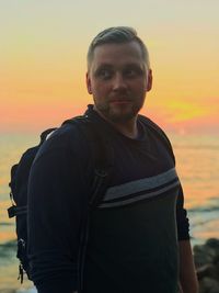 Portrait of man standing against orange sky